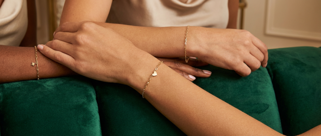 A tablet displaying an expert guide on how to start a permanent jewelry business alongside a professional pulse welder and jewelry supplies.